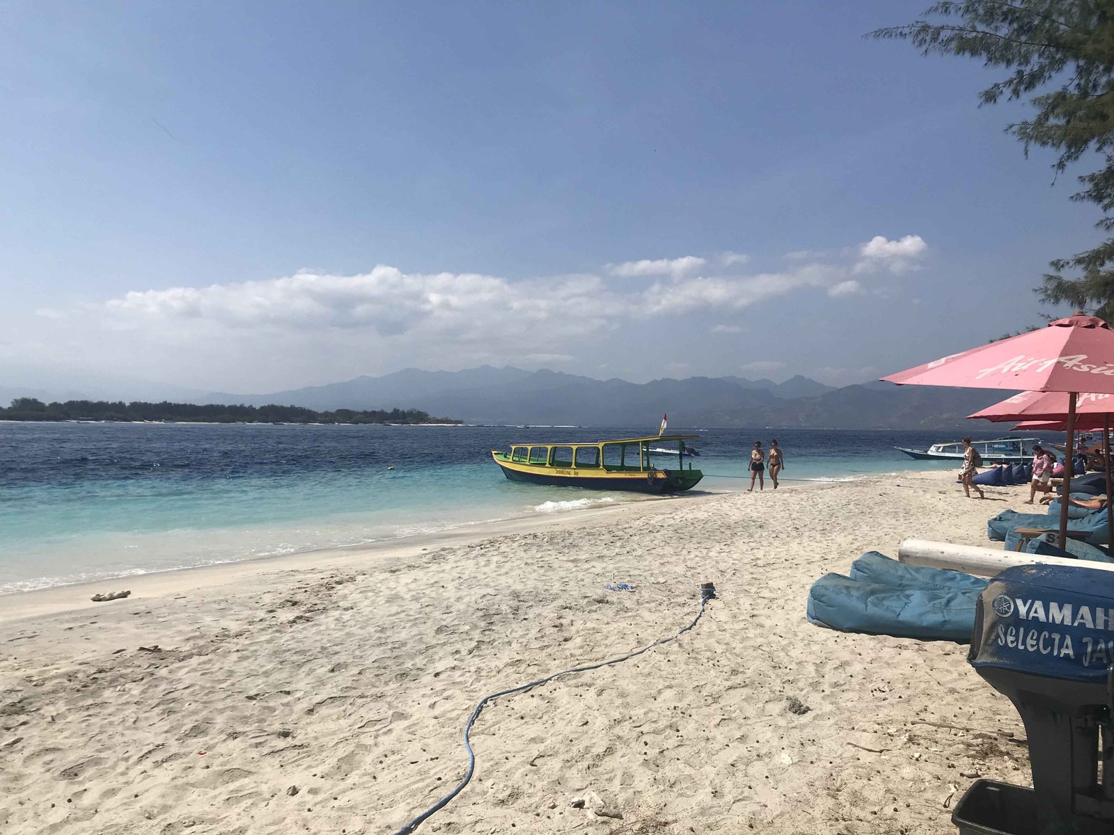 Speed boat is parked in clear water next to beach.