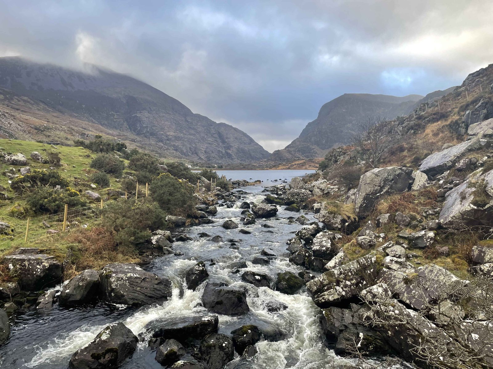 Water stream flowing from lake with mountains is background